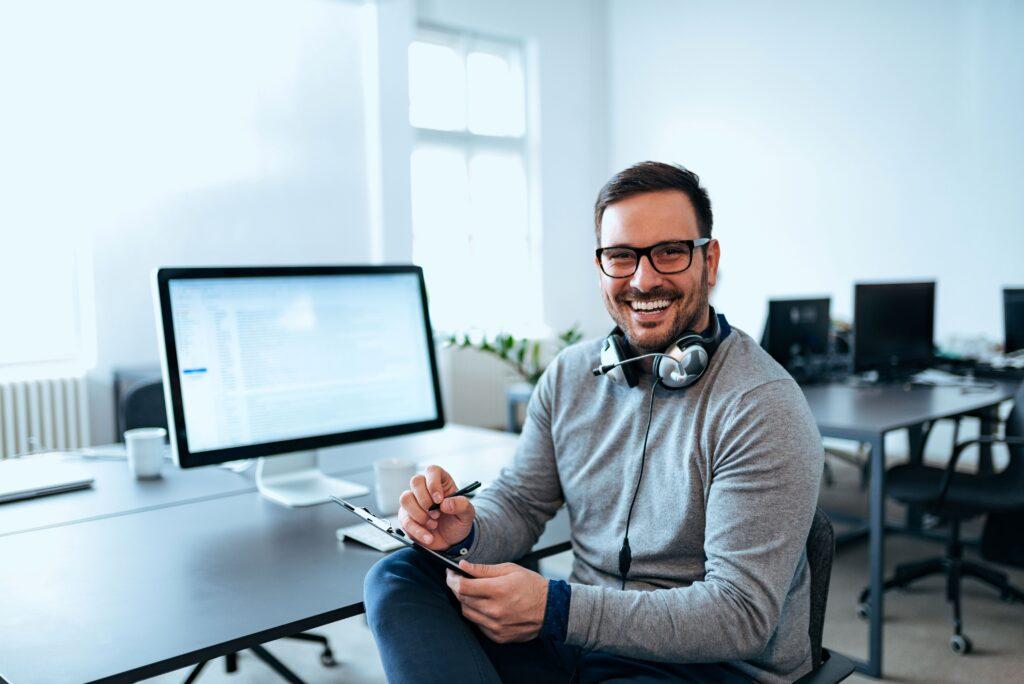 Ein lächelnder Mann sitzt vor einem Computer