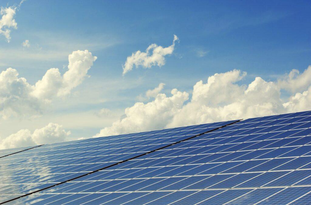 Große Solaranlage unter blauem Himmel mit weißen Wolken. Das Bild zeigt die Effektivität und Vorteile einer Solaranlage zum Festpreis für nachhaltige Energie.