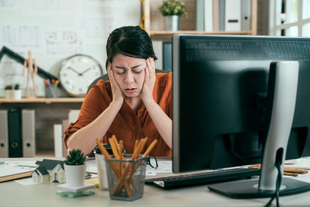 Eine Person sitzt vor ihrem Computer und ist kaputt aufgrund von der Lautstärke