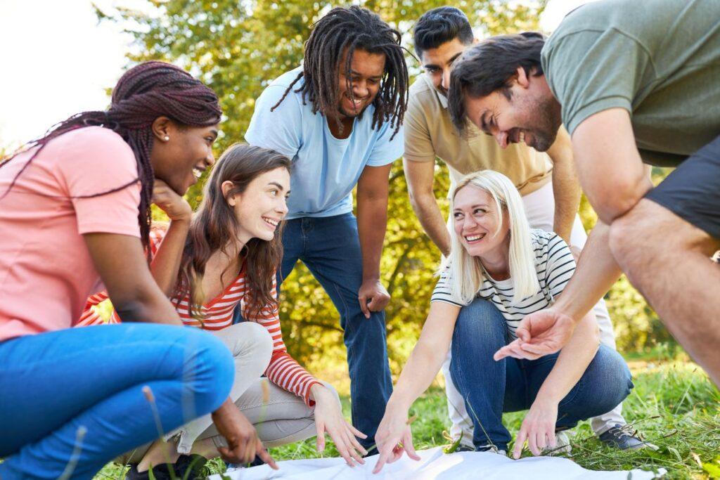 Junge Gruppe arbeitet gemeinsam an einer Karte bei Outdoor-Teamaufgabe mit Softair-Elementen zur Foerderung von Taktik und Gruppendynamik